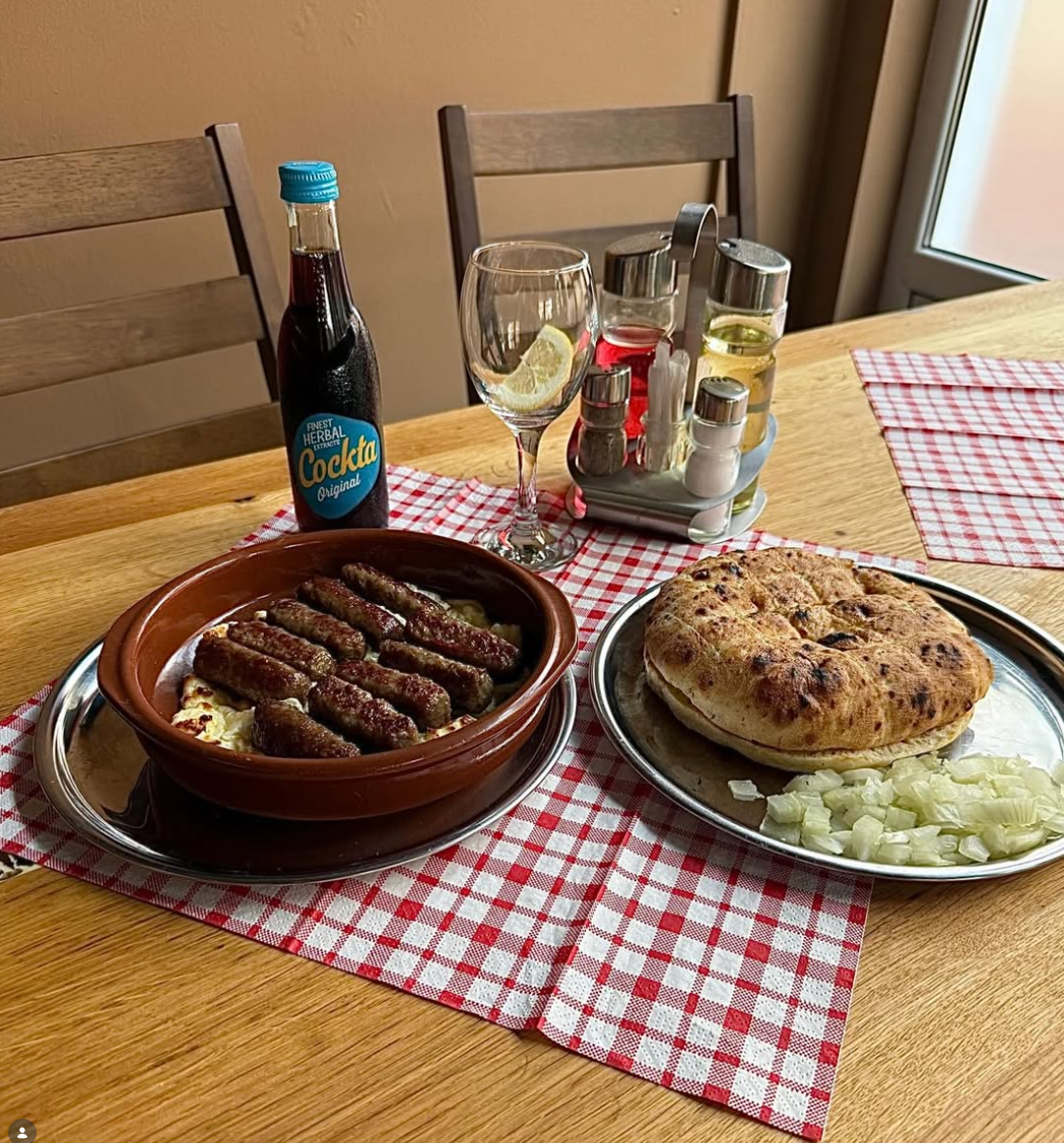 Ćevapčići im Tontopf mit Käse, dazu Fladenbrot und Cockta